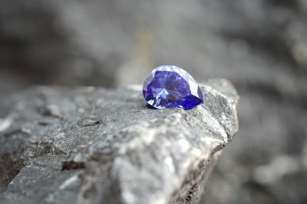Glimmering natural purple sapphire gemstone on a rock surface Glimmering natural purple sapphire gemstone on a rock surface